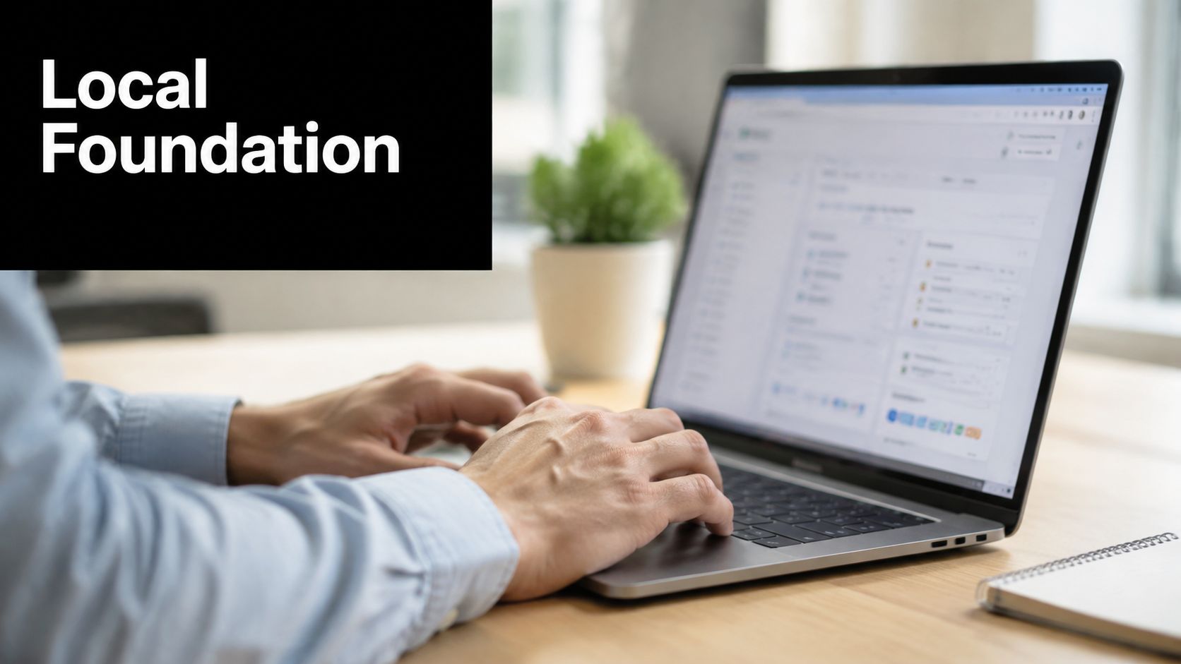 A professional using a laptop for digital marketing work at a clean, modern wooden office desk.